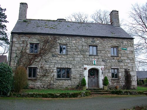 Large stone house with slate roof and chimney at each gable. (cy)